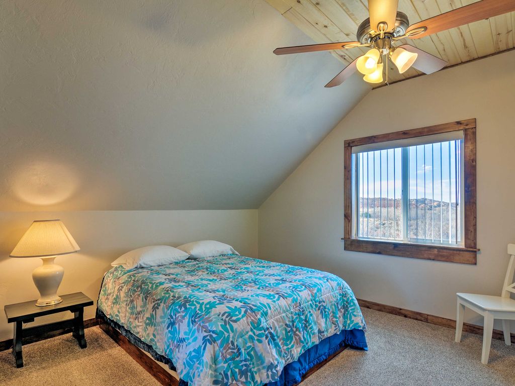 The first bedroom at Sunrise Hollow features a comfy queen bed, ceiling fan, knotty aspen lined ceiling, and panoramic views of red rock country in the distance.